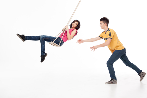 Man pushing girl on swing